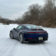a blue 2023 porsche 911 carrera on a snow-covered road in michigan